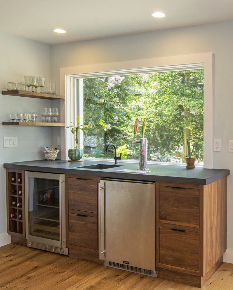 This is an example of a mid-sized transitional single-wall wet bar in Baltimore with an integrated sink, flat-panel cabinets, medium wood cabinets, concrete benchtops, light hardwood floors and brown floor.