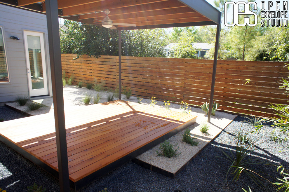 Mid-sized modern backyard partial sun xeriscape in Austin with gravel and a retaining wall.