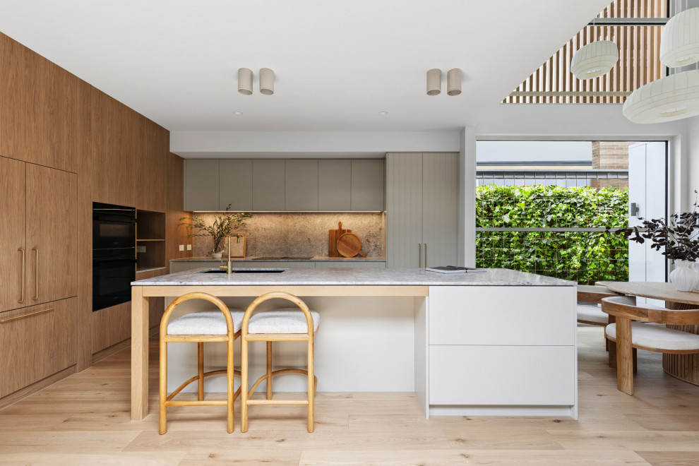 Design ideas for a small contemporary l-shaped open plan kitchen in Geelong with an undermount sink, marble benchtops, grey splashback, marble splashback, black appliances, light hardwood floors, with island, grey benchtop, flat-panel cabinets, beige floor and grey cabinets.