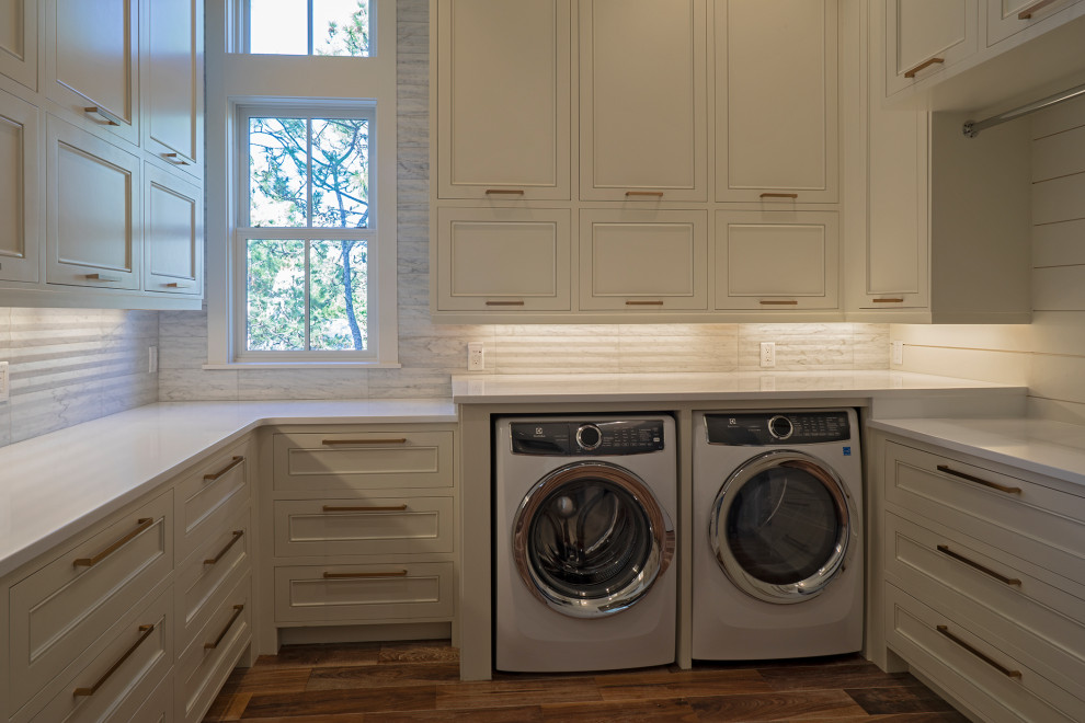 Design ideas for a large beach style u-shaped dedicated laundry room in Other with recessed-panel cabinets, white cabinets, grey splashback, matchstick tile splashback, white walls, medium hardwood floors, a side-by-side washer and dryer, brown floor, white benchtop and planked wall panelling.