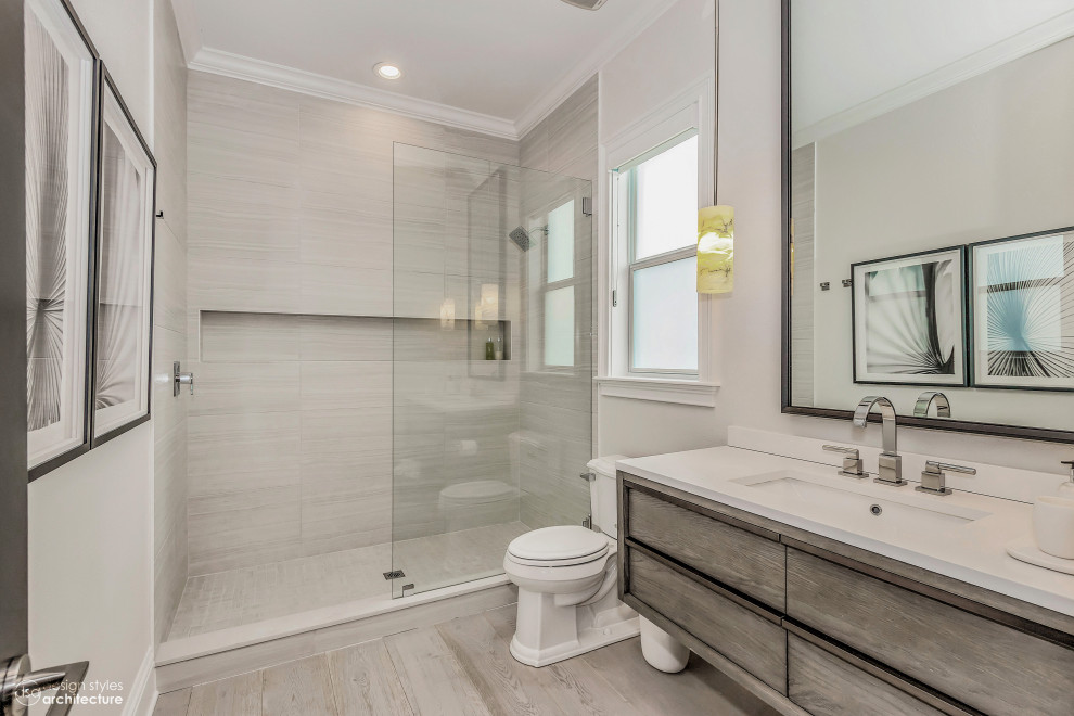 Inspiration for a small modern 3/4 bathroom in Tampa with flat-panel cabinets, light wood cabinets, an open shower, a one-piece toilet, grey walls, light hardwood floors, a drop-in sink, engineered quartz benchtops, brown floor, an open shower, white benchtops, an enclosed toilet, a double vanity and a built-in vanity.
