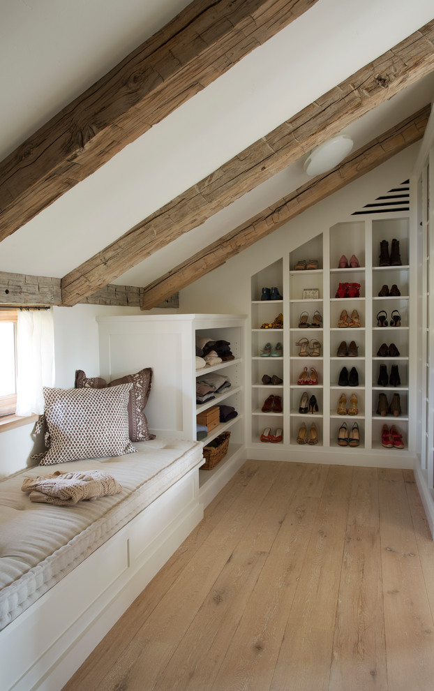 Inspiration for a mid-sized country gender-neutral walk-in wardrobe in Boston with open cabinets, white cabinets, light hardwood floors and brown floor.
