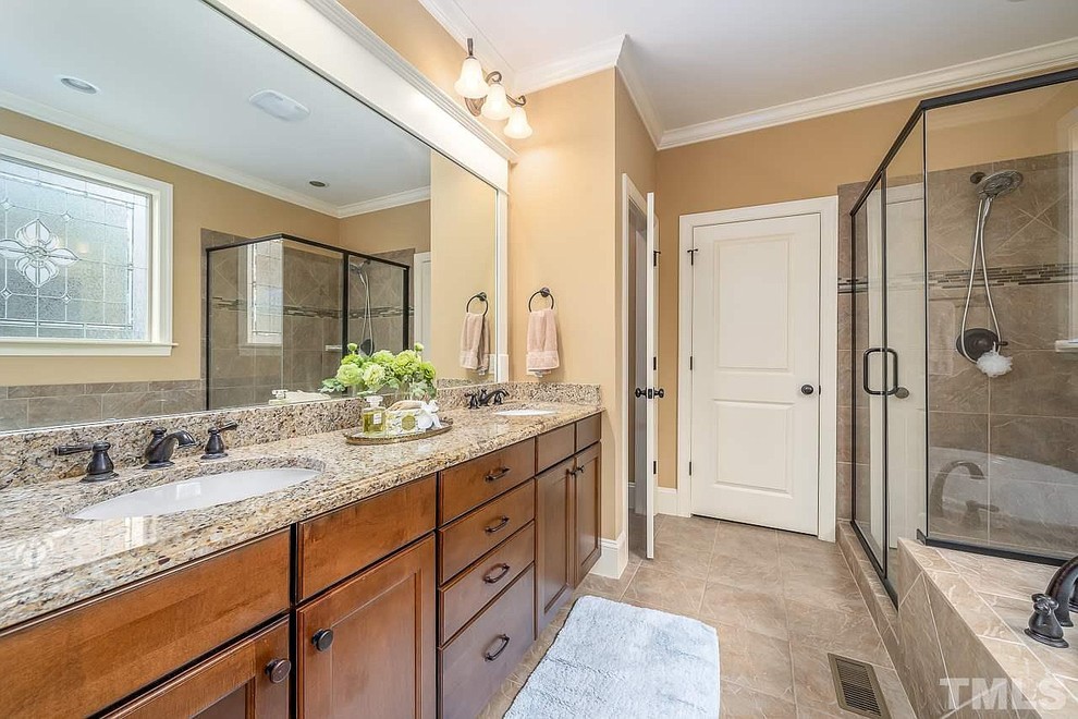 Design ideas for a mid-sized traditional master bathroom in Raleigh with recessed-panel cabinets, medium wood cabinets, a corner shower, beige walls, an undermount sink, granite benchtops, a hinged shower door and multi-coloured benchtops.