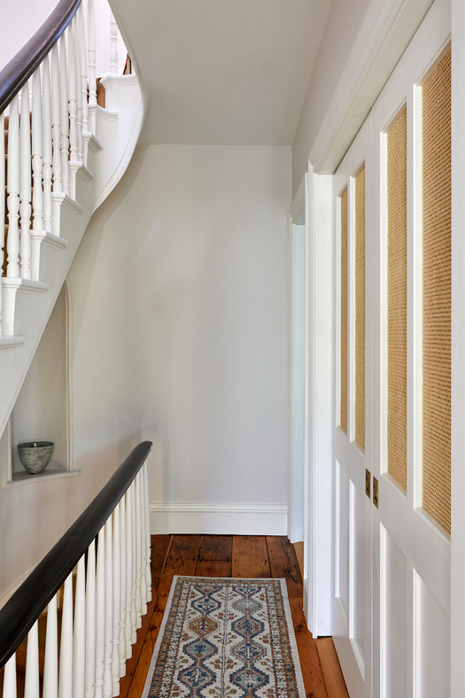 Example of a mid-sized classic medium tone wood floor and brown floor hallway design in New York with white walls