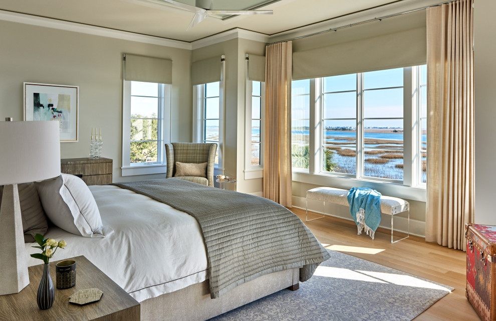 Ejemplo de dormitorio principal costero grande sin chimenea con paredes blancas, suelo de madera clara, suelo beige, bandeja y papel pintado