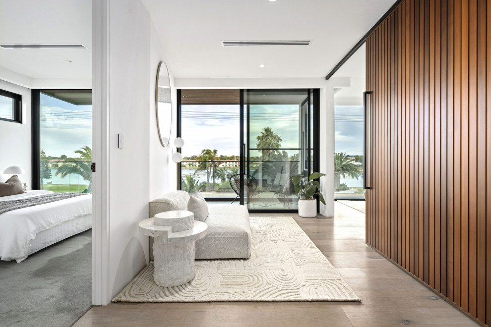 Imagen de dormitorio principal costero grande con paredes blancas, suelo de madera clara y suelo beige