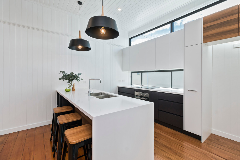 Design ideas for a mid-sized contemporary galley open plan kitchen in Brisbane with an undermount sink, flat-panel cabinets, medium wood cabinets, quartz benchtops, multi-coloured splashback, glass sheet splashback, stainless steel appliances, medium hardwood floors and with island.