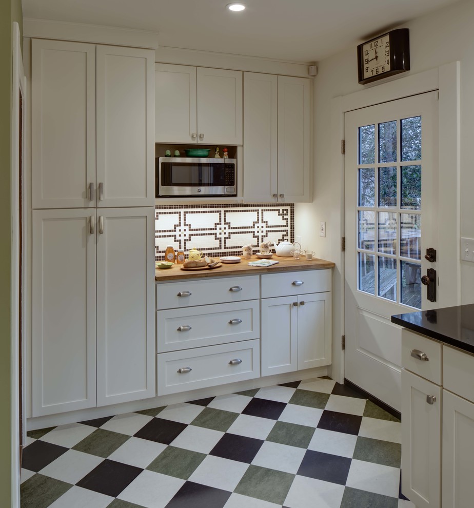 Inspiration for a mid-sized transitional l-shaped separate kitchen in New York with an undermount sink, shaker cabinets, white cabinets, white splashback, mosaic tile splashback, stainless steel appliances, linoleum floors, no island and wood benchtops.