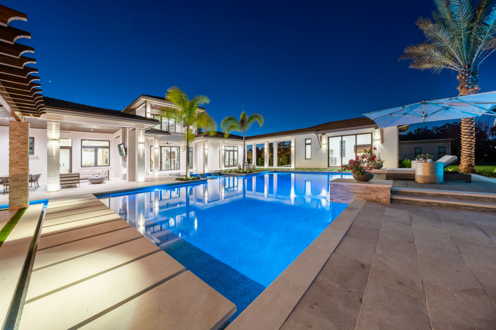 Photo of an expansive mediterranean backyard custom-shaped infinity pool in Tampa with with a pool and tile.