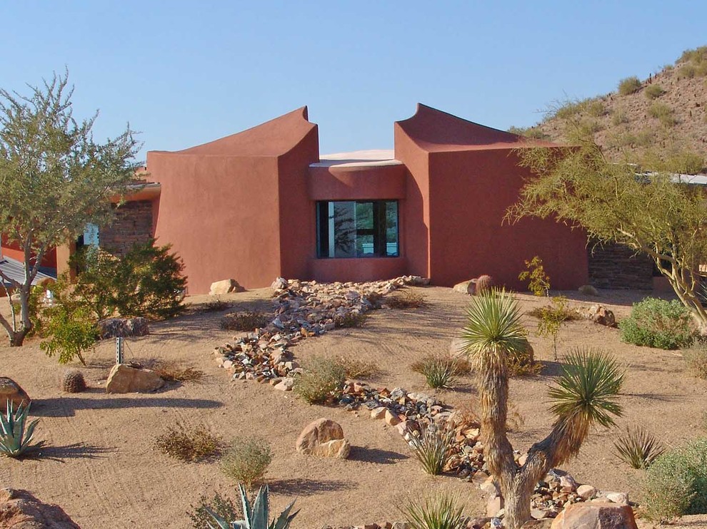 Photo of a small contemporary two-storey stucco orange house exterior in Phoenix with a flat roof and a green roof.