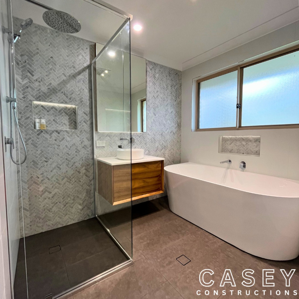 Mid-sized modern master bathroom in Brisbane with furniture-like cabinets, white cabinets, a corner tub, a corner shower, gray tile, ceramic tile, grey walls, ceramic floors, a console sink, laminate benchtops, grey floor, a hinged shower door, white benchtops, a single vanity, a built-in vanity, wallpaper and panelled walls.