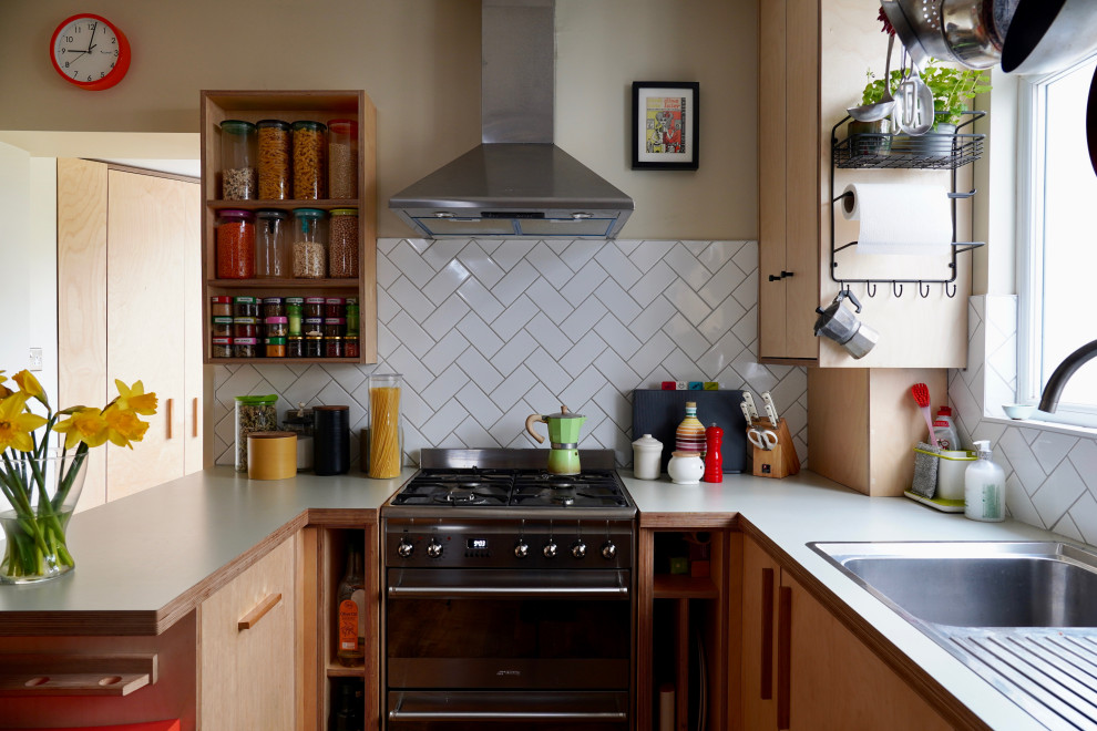 Small scandi l-shaped kitchen in Sussex with flat-panel cabinets, laminate countertops, white splashback, ceramic splashback, stainless steel appliances and white worktops.