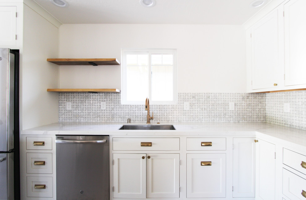Mid-sized l-shaped light wood floor and brown floor open concept kitchen photo with an undermount sink, shaker cabinets, white cabinets, quartz countertops, gray backsplash, mosaic tile backsplash, stainless steel appliances, an island and white countertops