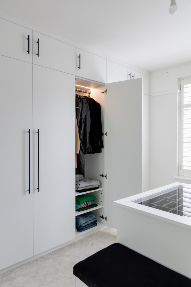 Idee per una cabina armadio minimalista di medie dimensioni con ante lisce, ante bianche, moquette e pavimento grigio