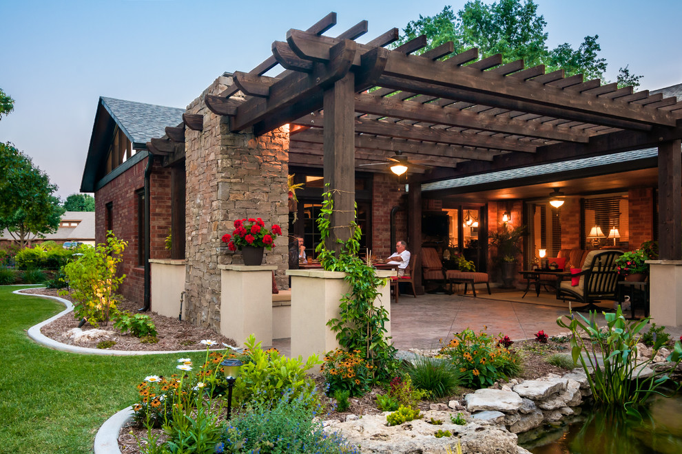 Large traditional backyard patio in Oklahoma City with a pergola and concrete pavers.