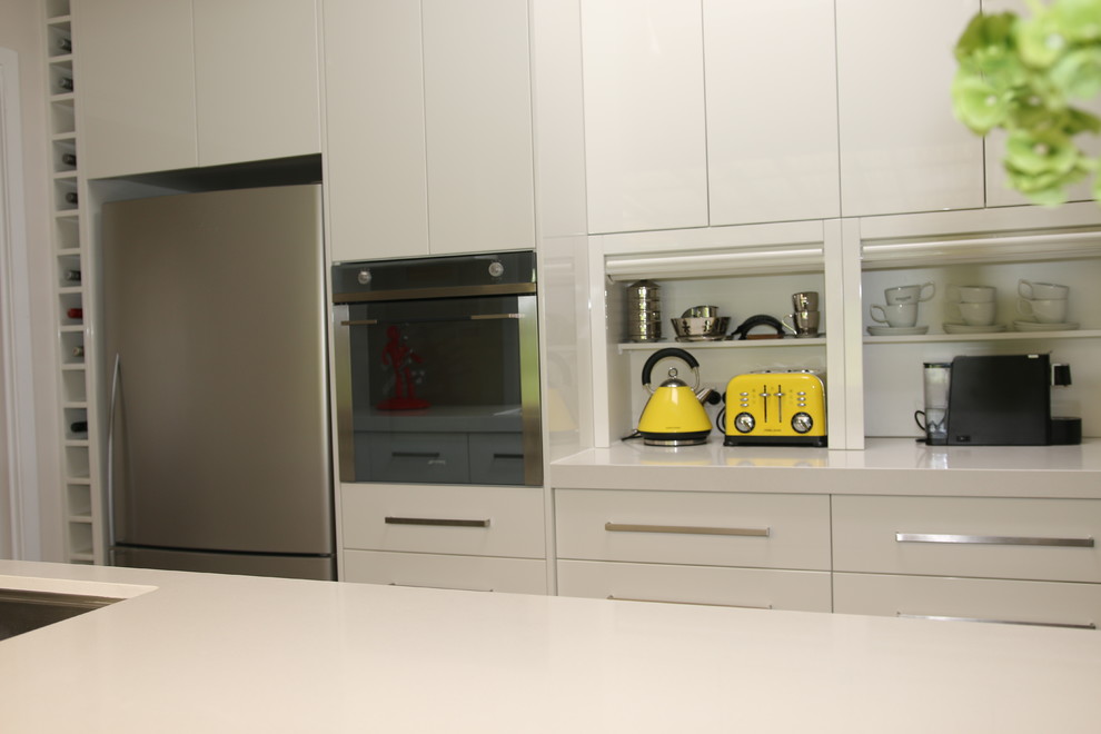 This is an example of a large modern galley kitchen pantry in Sydney with an undermount sink, flat-panel cabinets, white cabinets, quartz benchtops, brown splashback, glass sheet splashback, stainless steel appliances, slate floors and no island.