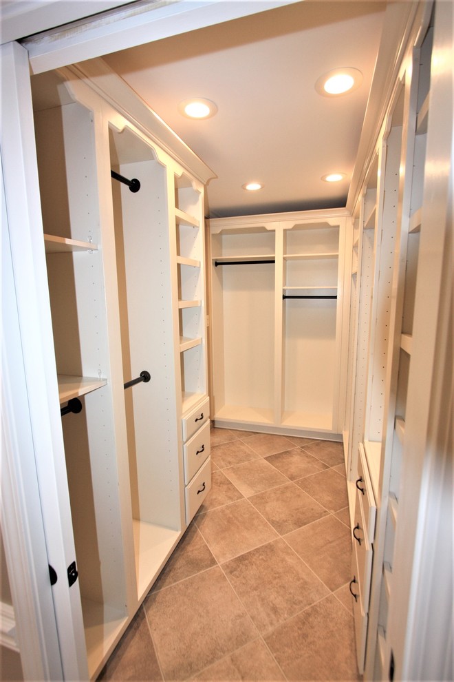 Photo of a large traditional storage and wardrobe in Other with raised-panel cabinets, white cabinets and porcelain floors.