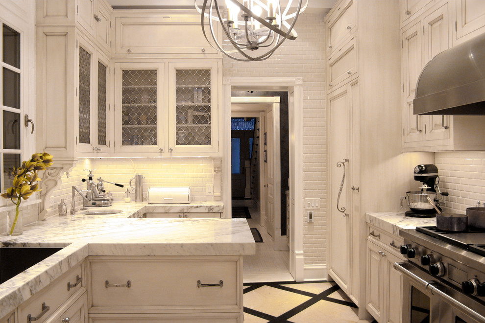 This is an example of a traditional galley separate kitchen in Chicago with panelled appliances, subway tile splashback, an undermount sink, white splashback, marble benchtops and recessed-panel cabinets.