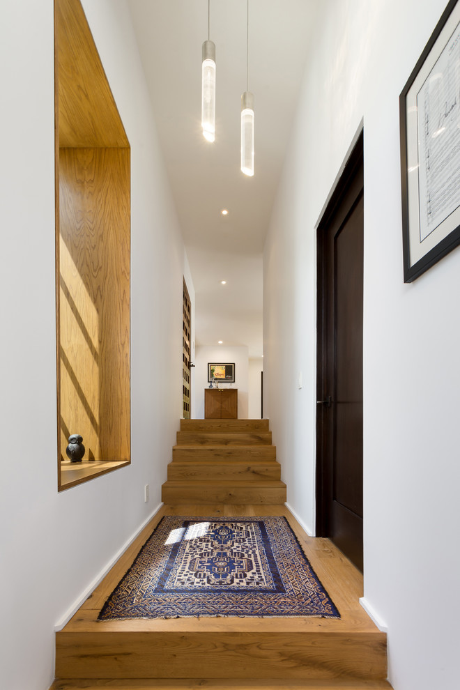 This is an example of a mid-sized mediterranean vestibule in Los Angeles with white walls, light hardwood floors, a single front door, a medium wood front door and yellow floor.