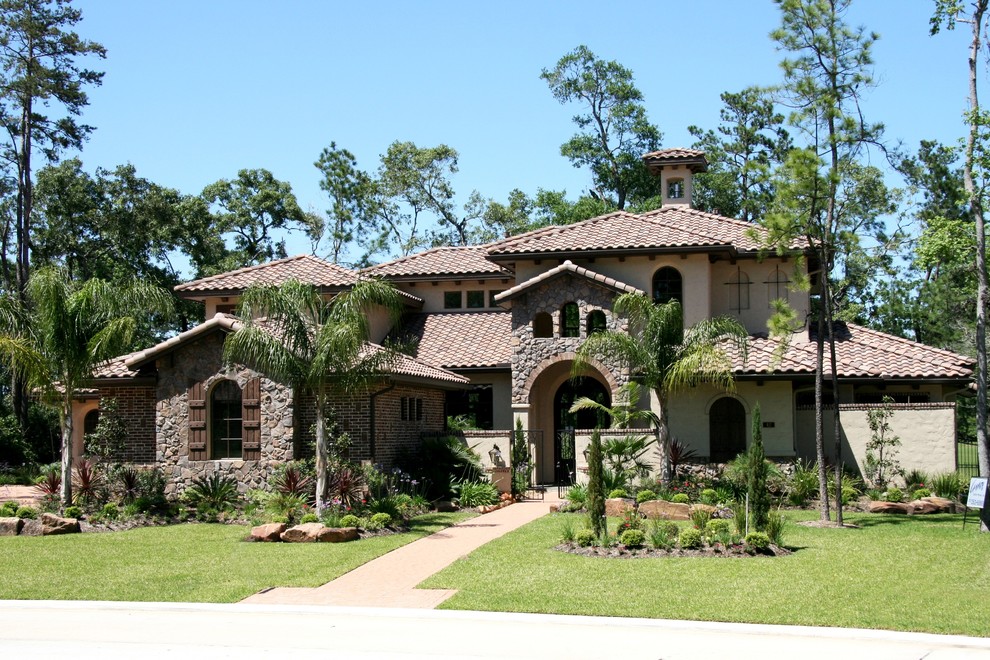 This is an example of a large mediterranean two-storey beige exterior in Houston with mixed siding.