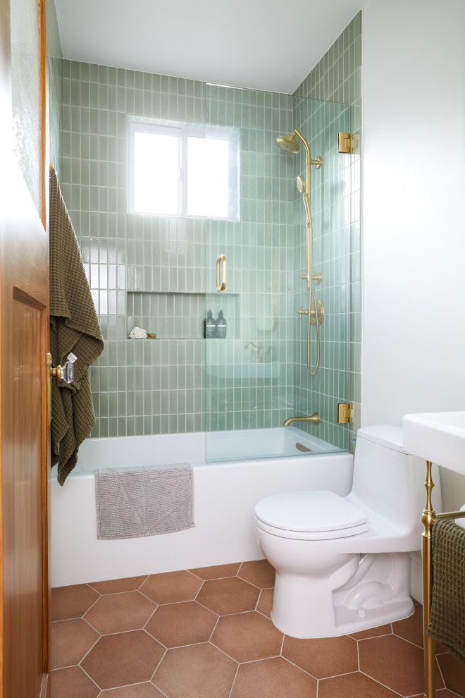 Small traditional bathroom in San Francisco with white cabinets, an alcove tub, a shower/bathtub combo, a one-piece toilet, green tile, ceramic tile, white walls, ceramic floors, a pedestal sink, orange floor, a hinged shower door, a niche, a single vanity and a freestanding vanity.