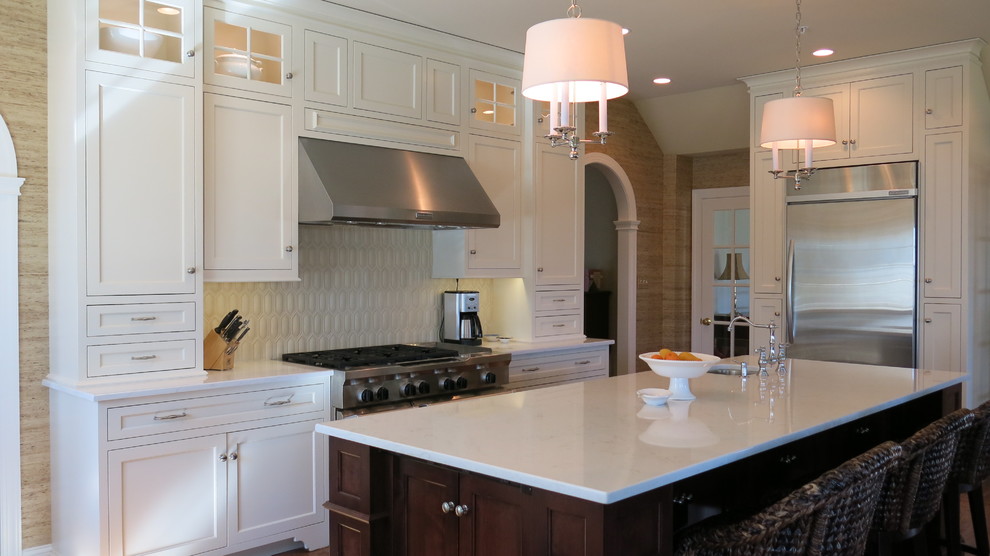 Example of a transitional kitchen design with white cabinets, quartz countertops and white backsplash