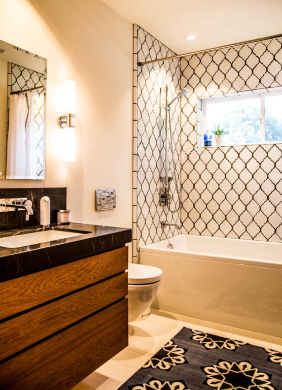 Mid-sized modern bathroom in San Francisco with an undermount sink, flat-panel cabinets, medium wood cabinets, marble benchtops, a drop-in tub, a wall-mount toilet, white tile, ceramic tile, beige walls and limestone floors.