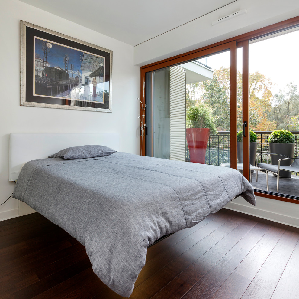 This is an example of a contemporary bedroom in Paris with white walls and dark hardwood floors.