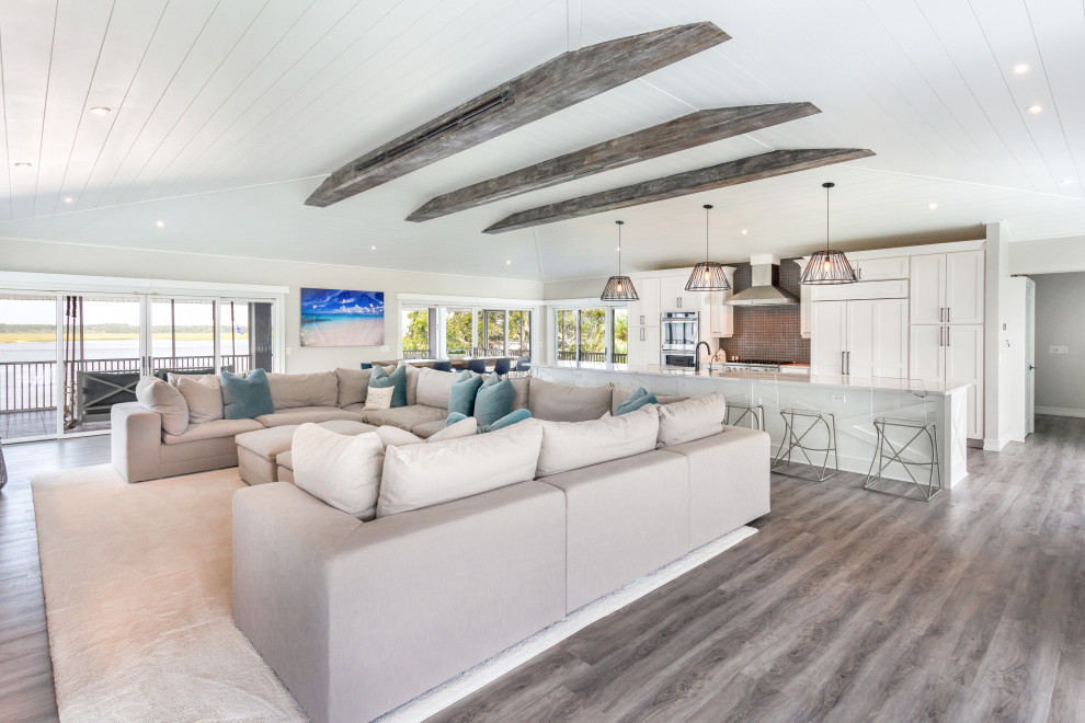 Design ideas for an expansive beach style open concept family room in Jacksonville with beige walls, vinyl floors, a built-in media wall, multi-coloured floor and exposed beam.