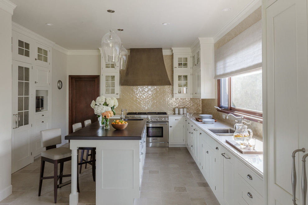 Photo of a mid-sized traditional l-shaped separate kitchen in San Francisco with an undermount sink, shaker cabinets, white cabinets, beige splashback, with island, beige floor, solid surface benchtops and travertine floors.