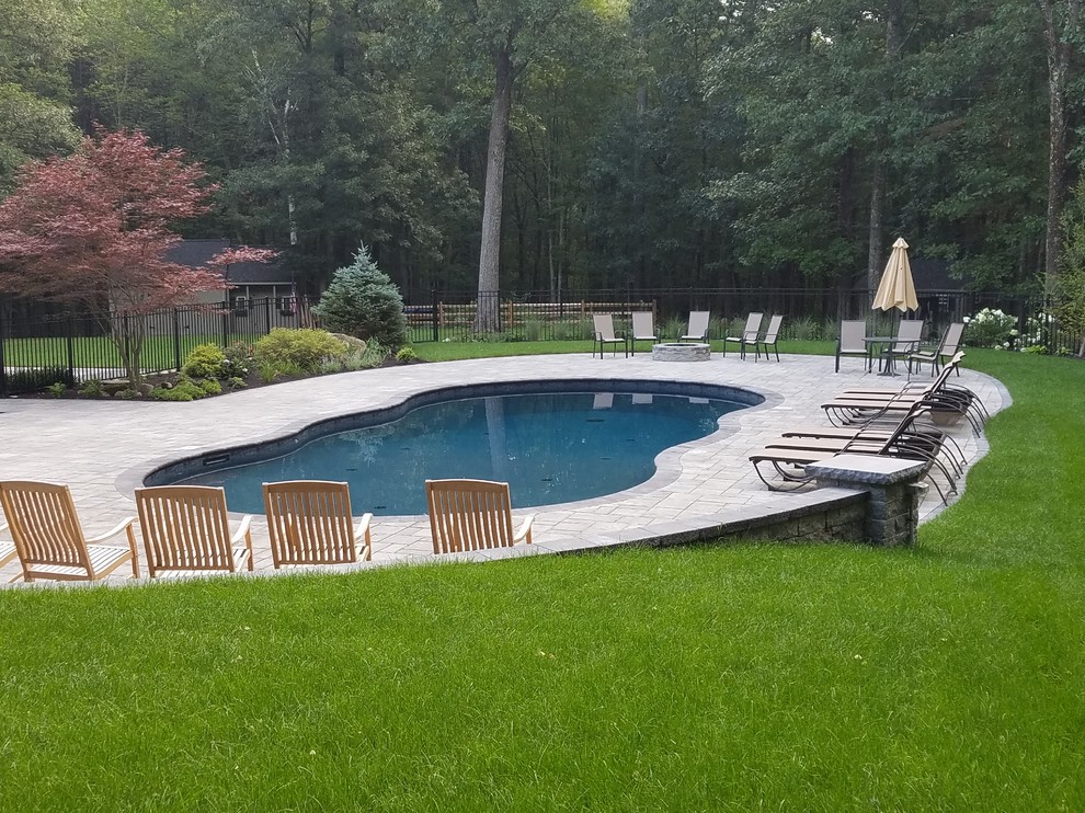 Photo of a mid-sized transitional backyard custom-shaped lap pool in Boston with concrete pavers.