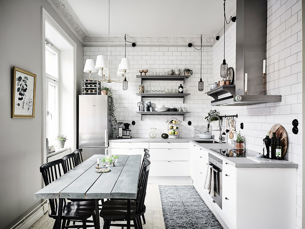 Mid-sized scandinavian l-shaped eat-in kitchen in Gothenburg with a single-bowl sink, flat-panel cabinets, white cabinets, concrete benchtops, stainless steel appliances, light hardwood floors and no island.
