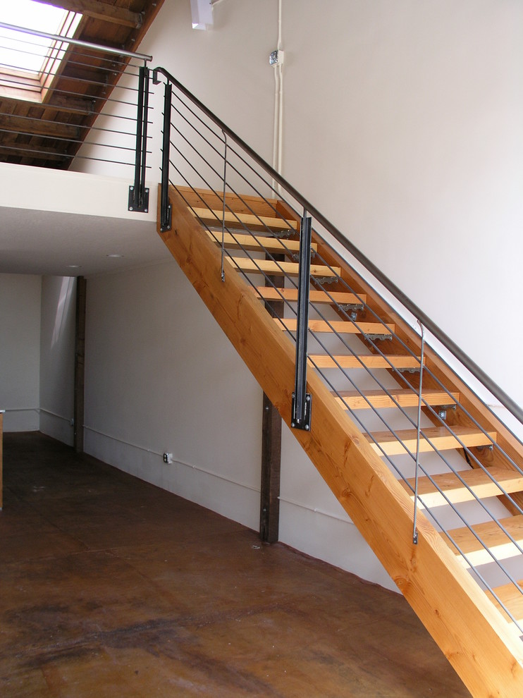 Design ideas for a large industrial wood u-shaped staircase in San Francisco with wood risers and metal railing.