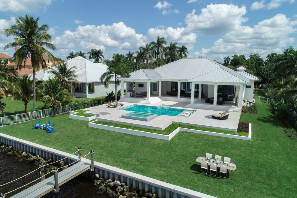 Photo of a large contemporary backyard rectangular lap pool in Miami with a hot tub and tile.