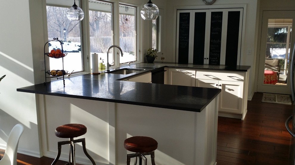 Inspiration for a mid-sized transitional u-shaped dark wood floor eat-in kitchen remodel with a single-bowl sink, recessed-panel cabinets, white cabinets, granite countertops, white backsplash, ceramic backsplash and stainless steel appliances