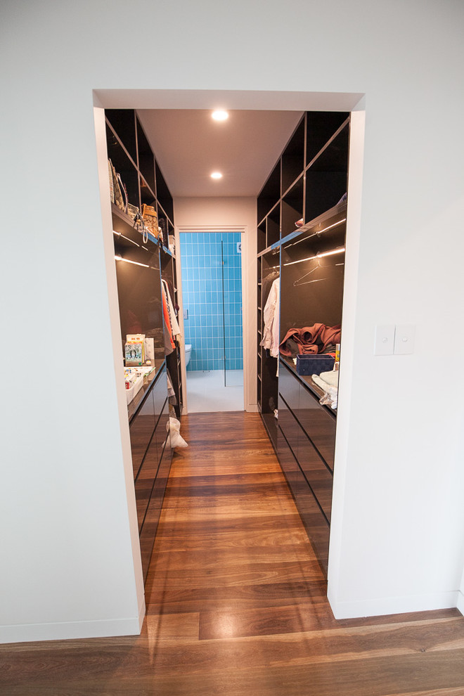 Inspiration for a large contemporary gender-neutral walk-in wardrobe in Sydney with open cabinets, black cabinets and light hardwood floors.