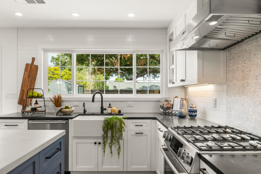 Design ideas for a large contemporary l-shaped eat-in kitchen in San Francisco with a farmhouse sink, shaker cabinets, white cabinets, soapstone benchtops, white splashback, porcelain splashback, stainless steel appliances, vinyl floors, with island, brown floor and black benchtop.