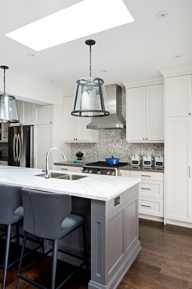 Example of a mid-sized transitional single-wall dark wood floor eat-in kitchen design in Toronto with an undermount sink, shaker cabinets, white cabinets, quartz countertops, gray backsplash, mosaic tile backsplash, stainless steel appliances and an island