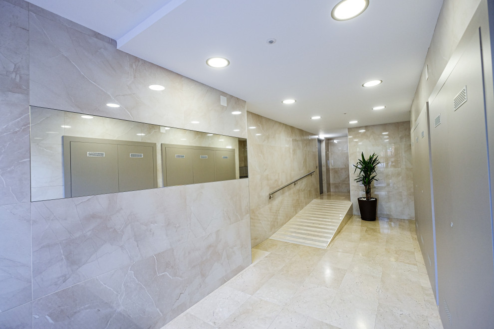 Photo of a mid-sized transitional vestibule in Barcelona with beige walls, marble floors, a single front door, a glass front door and beige floor.