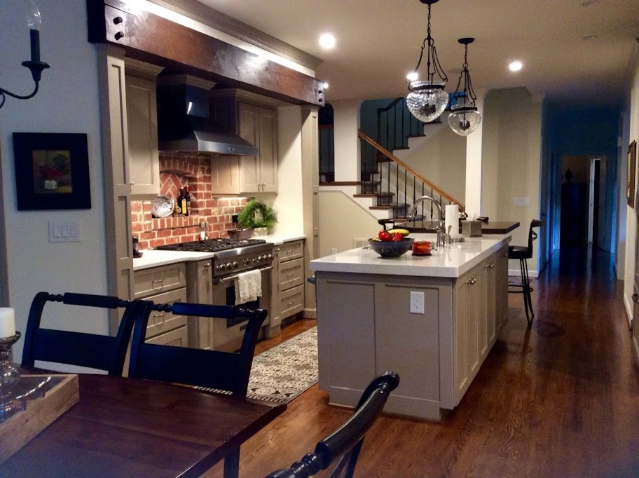 This is an example of a mid-sized transitional galley eat-in kitchen in Raleigh with an undermount sink, shaker cabinets, beige cabinets, quartz benchtops, red splashback, brick splashback, stainless steel appliances, dark hardwood floors and with island.