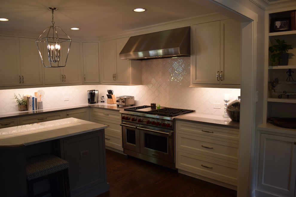 This is an example of a large transitional u-shaped eat-in kitchen in Chicago with beaded inset cabinets, white cabinets, quartz benchtops, white splashback and multiple islands.