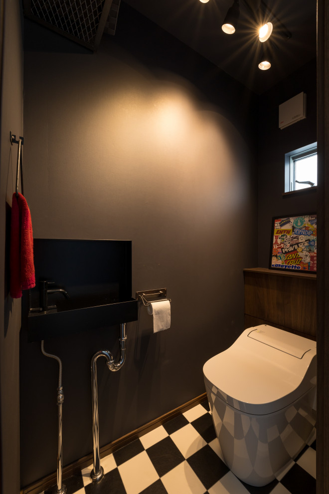 Moderne Gästetoilette mit schwarzen Schränken, Toilette mit Aufsatzspülkasten, schwarzer Wandfarbe, Vinylboden, Wandwaschbecken, Mineralwerkstoff-Waschtisch, schwarzem Boden, eingebautem Waschtisch, Tapetendecke und Tapetenwänden in Sonstige