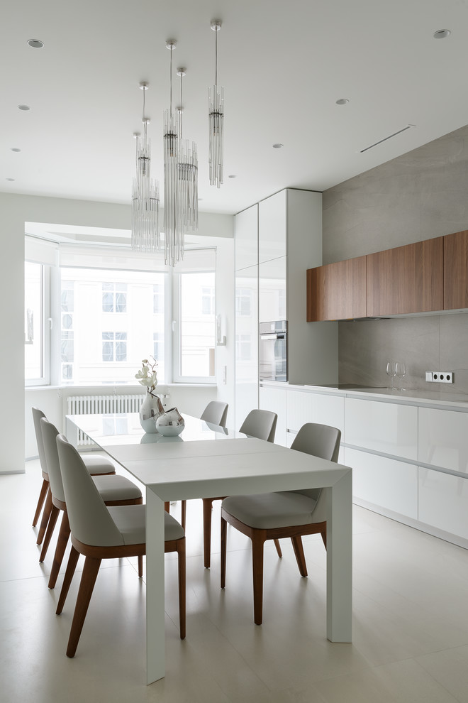 Inspiration for a mid-sized contemporary single-wall eat-in kitchen in Saint Petersburg with an undermount sink, flat-panel cabinets, white cabinets, glass benchtops, grey splashback, porcelain splashback, black appliances, porcelain floors, no island, grey floor and white benchtop.