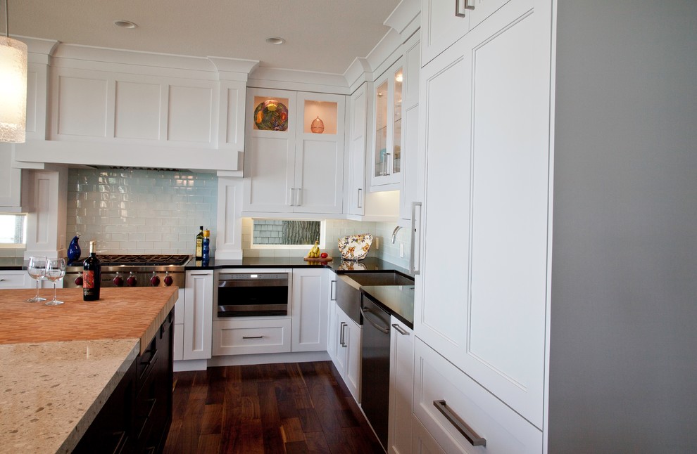 Inspiration for a large transitional l-shaped medium tone wood floor and brown floor eat-in kitchen remodel with a farmhouse sink, shaker cabinets, white cabinets, quartzite countertops, blue backsplash, glass sheet backsplash, stainless steel appliances and an island