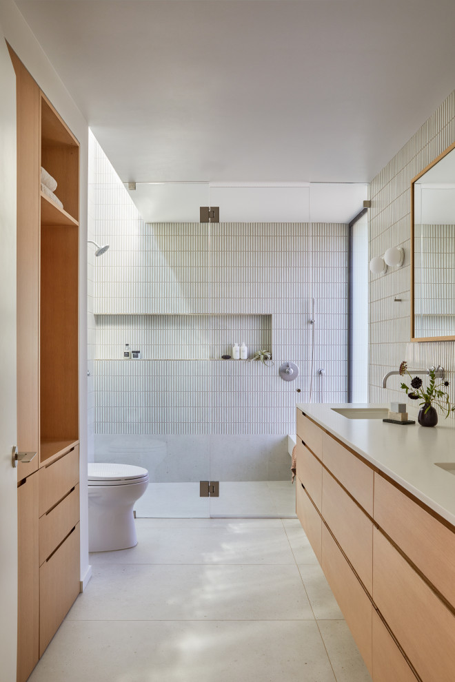 This is an example of a large modern master bathroom in San Francisco with flat-panel cabinets, brown cabinets, a curbless shower, a one-piece toilet, white tile, ceramic tile, white walls, porcelain floors, an undermount sink, engineered quartz benchtops, beige floor, a hinged shower door, grey benchtops, a shower seat, a double vanity and a floating vanity.