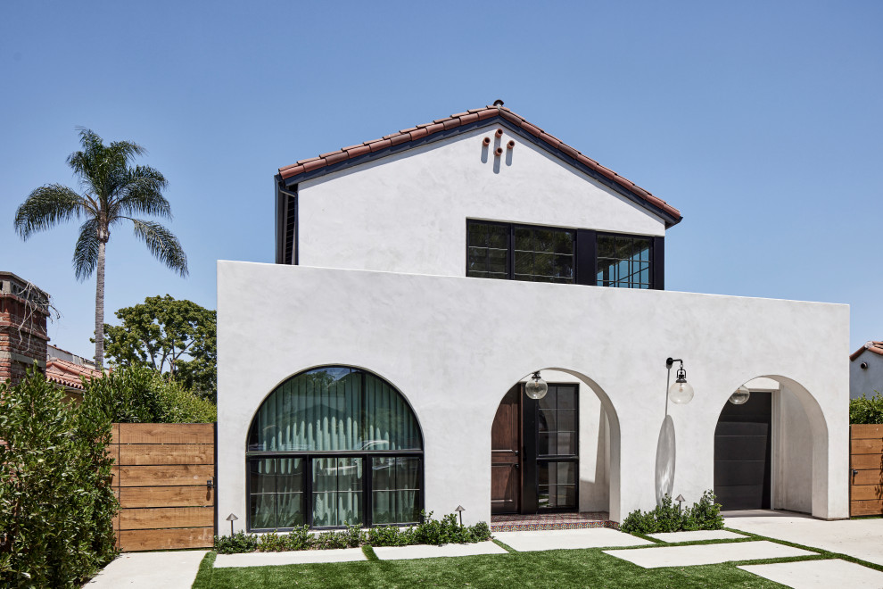 Mittelgroßes, Zweistöckiges Mediterranes Einfamilienhaus mit Putzfassade, weißer Fassadenfarbe, Satteldach, Ziegeldach und rotem Dach in Los Angeles