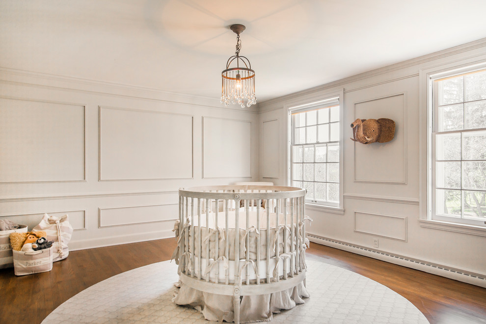 Example of a mid-sized transitional gender-neutral medium tone wood floor nursery design with white walls