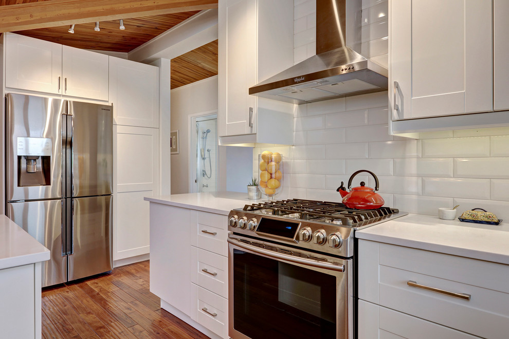 Inspiration for a transitional u-shaped medium tone wood floor eat-in kitchen remodel in Calgary with an undermount sink, shaker cabinets, white cabinets, quartzite countertops, white backsplash, subway tile backsplash, stainless steel appliances and an island