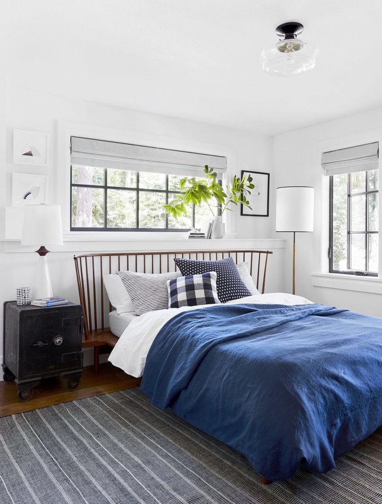 This is an example of a transitional bedroom in Portland Maine with white walls, medium hardwood floors and brown floor.