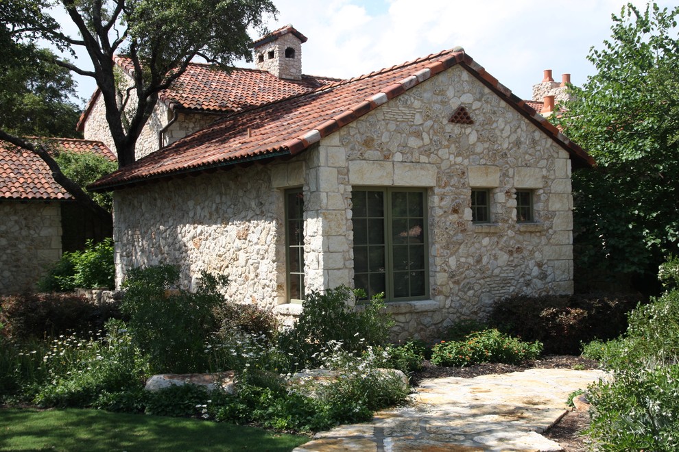 This is an example of a mediterranean two-storey exterior in Austin with stone veneer.